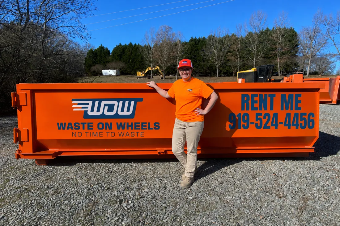 Waste On Wheels owner Logan standing beside a 15-yard roll-off dumpster for scale at the Willow Spring, NC yard